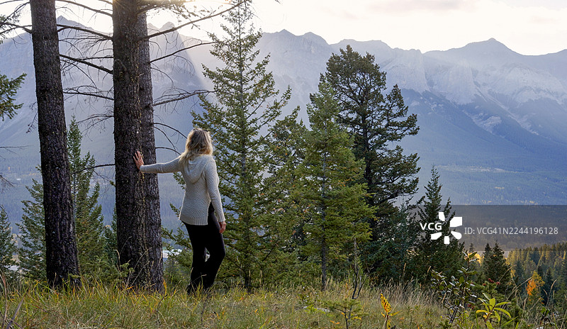 女子在山谷和山脉上方的草地上放松，卡尔加里图片素材