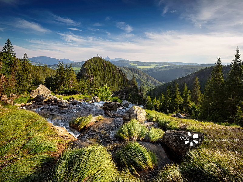 斯洛伐克，斯洛伐克天堂国家公园，蓝天下雄伟的山脉景观，伴有潺潺溪流和郁郁葱葱的绿色森林图片素材