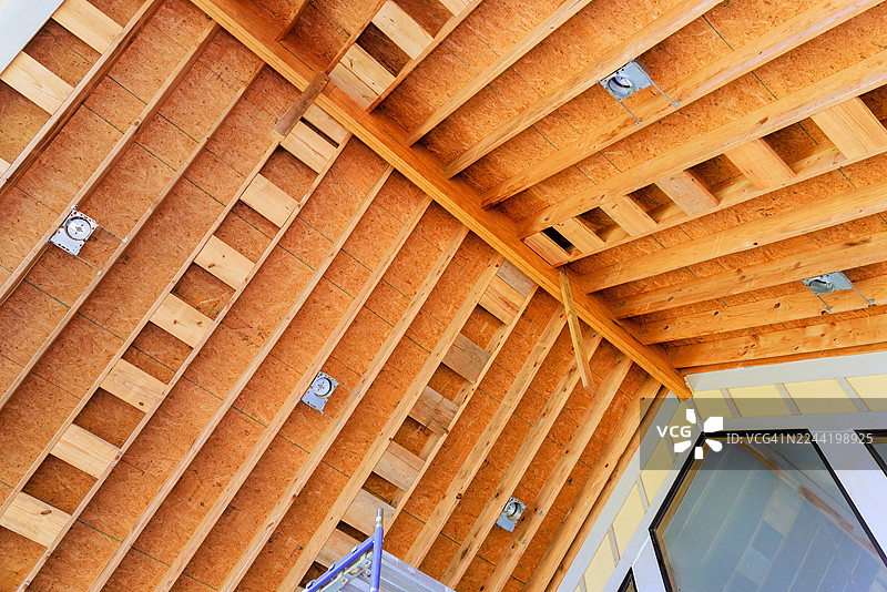 在建新房的低角度视图，展示了木制屋顶桁架和胶合板护墙板图片素材