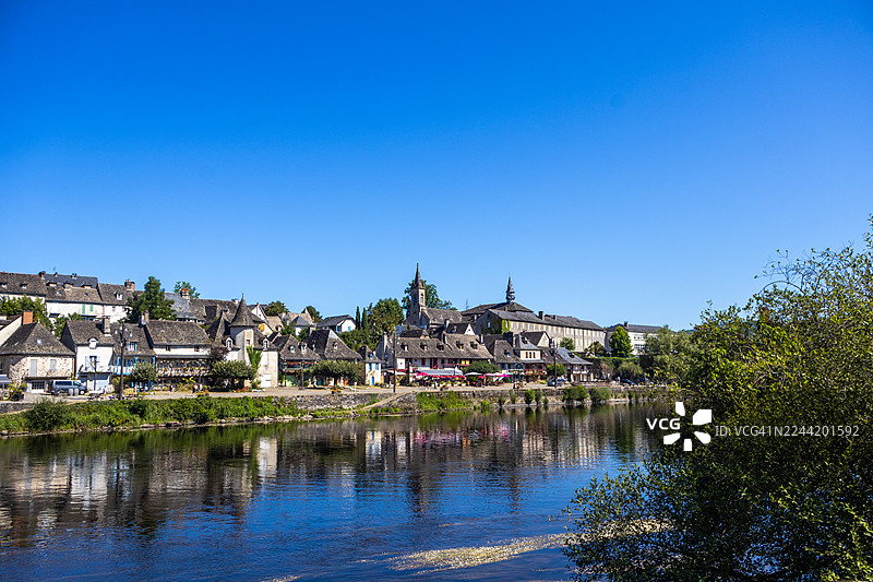 法国康塔尔风景如画的传统建筑小镇，在湛蓝天空下倒映于宁静的河流中图片素材