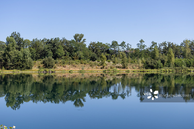 法国康塔尔宁静的夏日风光，碧蓝的天空倒映在平静的湖面上，四周环绕着郁郁葱葱的绿树。图片素材