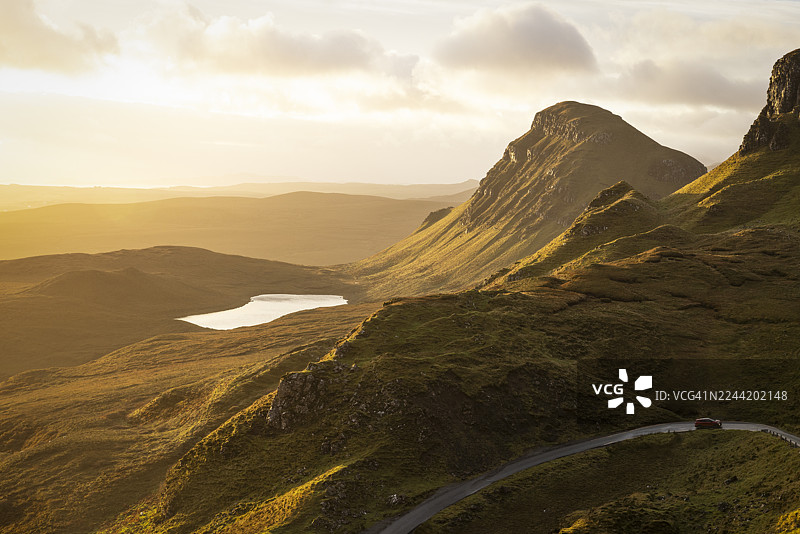 苏格兰崎岖山峰与宁静湖泊的景致，夕阳染红天际，金色的光辉描绘出苏格兰岛屿斯凯岛奎雷英的原始之美，英国。图片素材