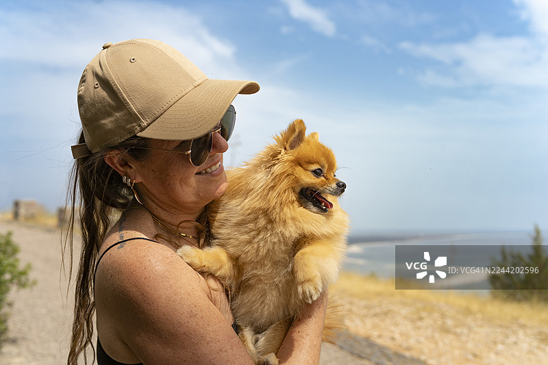 自然背景下，一位女士与博美犬的肖像照图片素材