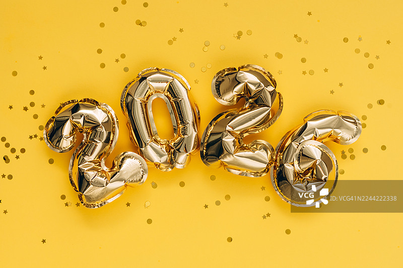 金色的2026气球和纸屑在黄色背景上图片素材