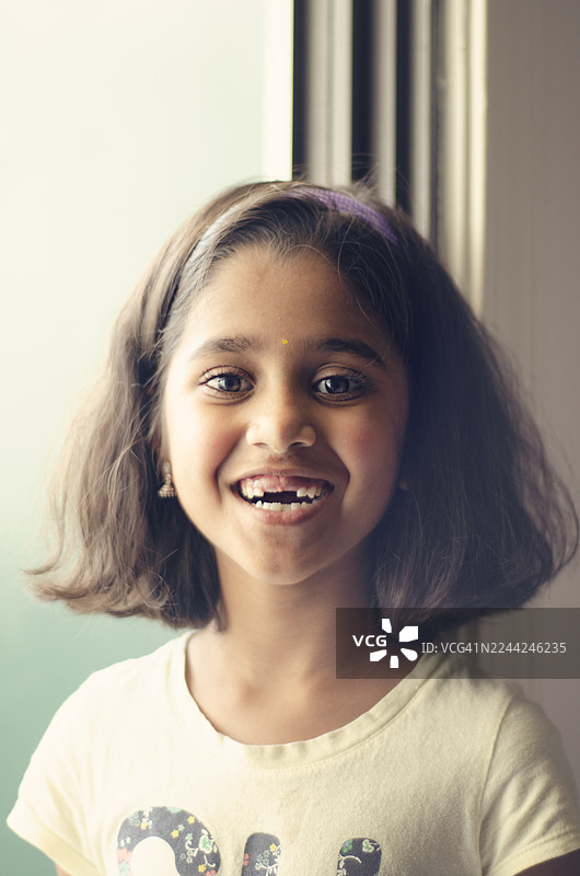 快乐的印度儿童的特写肖像，她正咧嘴微笑。她喜悦的表情和自然的容貌使这张图片非常适合表现童年、真实情感和多元化代表性等概念。图片素材