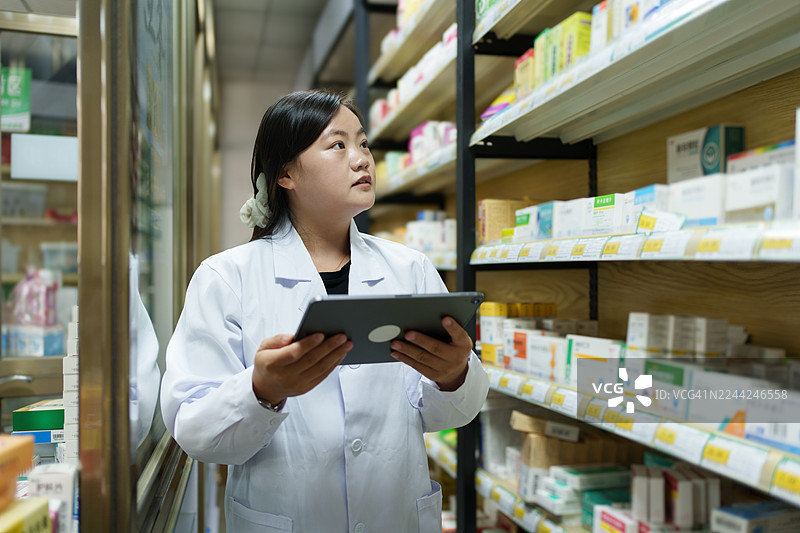 女药剂师正在检查货架上的药品。图片素材