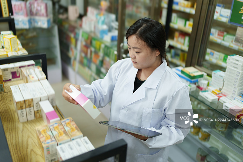 药店工作人员正在检查货架上的商品。图片素材