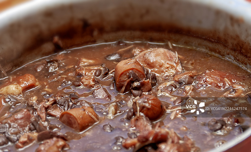 俯视视角，锅中的巴西黑豆炖肉（feijoada），一种典型的巴西菜肴，包含黑豆、各种肉类、培根和香肠。图片素材
