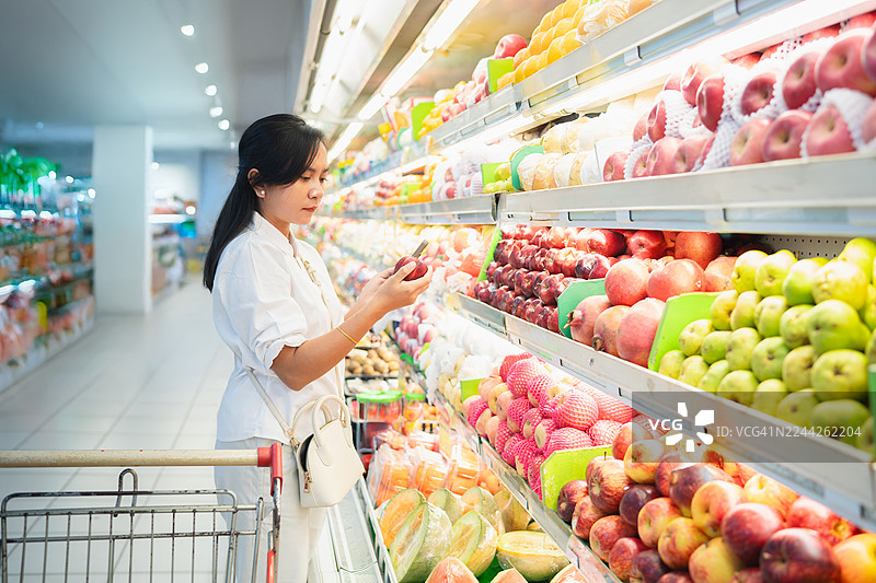 女子在超市挑选苹果图片素材