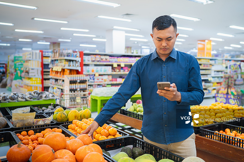 男士在超市用智能手机购物水果图片素材