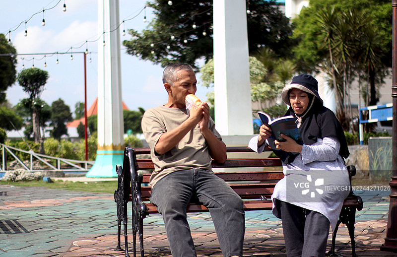 情侣在公园长椅上放松。图片素材