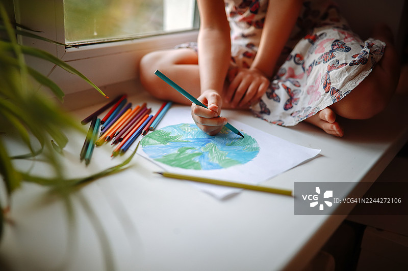 创意教育——小手正在仔细地用蓝色和绿色描绘大陆图片素材