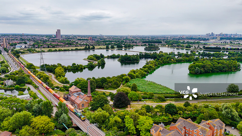 伦敦沃尔瑟姆斯托水库的空中视角，有货运列车和居民住宅经过，工业铁路与城市水景，交通与环境保护理念图片素材