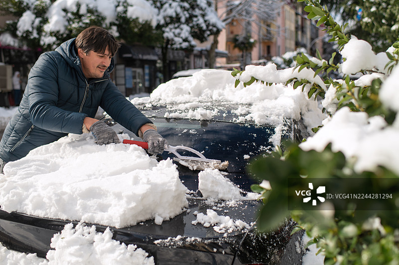 大雪过后，一名男子正在清洁他的汽车图片素材