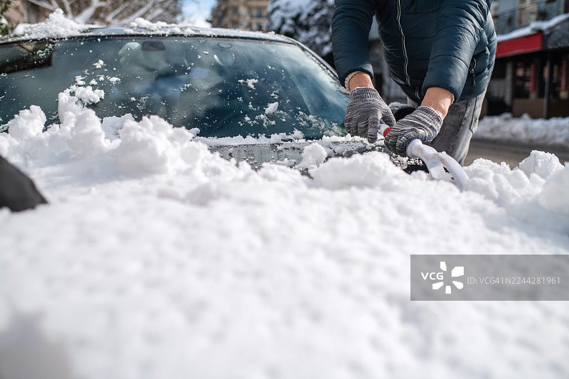 大雪过后，一名男子正在清洁他的汽车图片素材