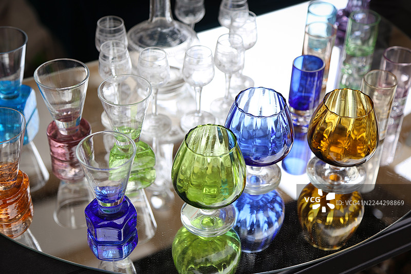 在当地跳蚤市场，镜子背景前摆放着复古水晶酒杯和老式烈酒杯图片素材