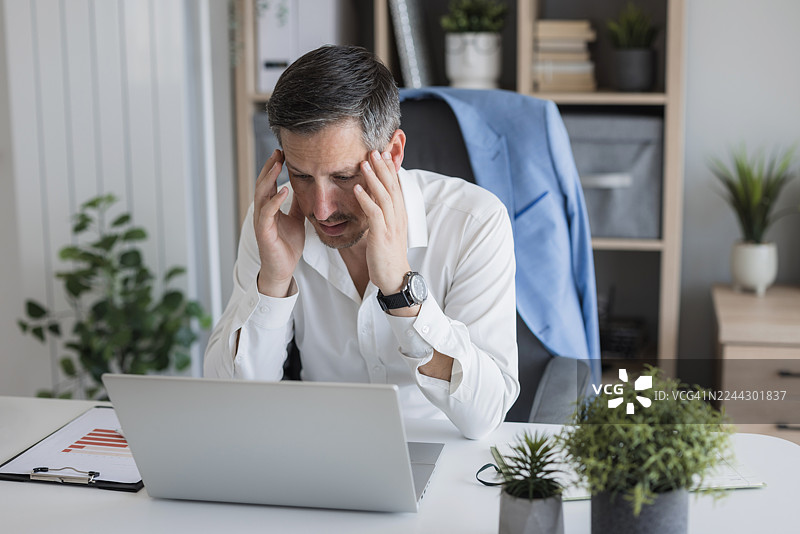 一位商人因工作压力和头痛而感到焦虑图片素材