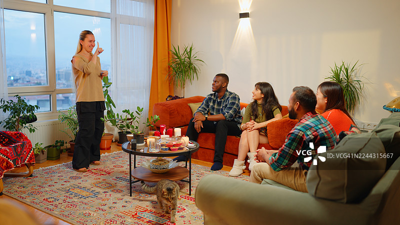 一群不同肤色的朋友在派对上开心地玩着猜谜游戏图片素材