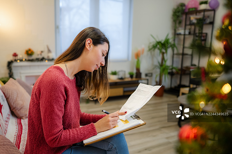 女人在家写圣诞预算并规划开支图片素材