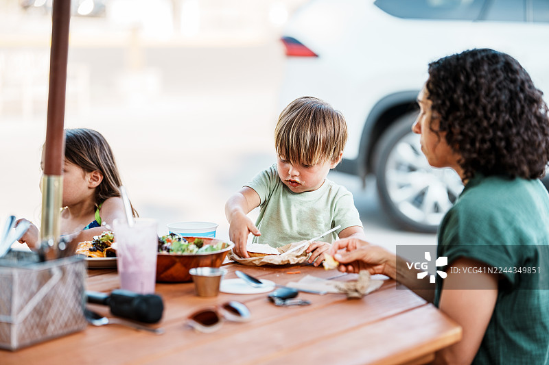 小男孩在餐馆里和家人一起在户外用餐图片素材