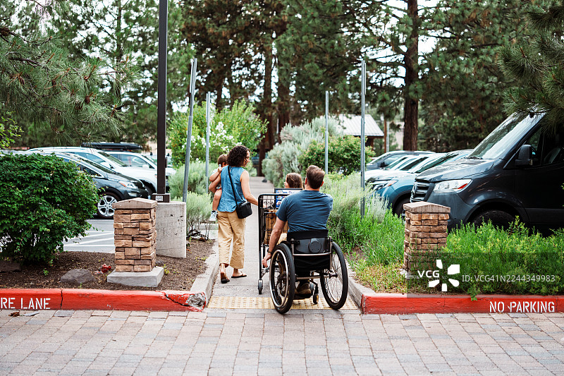 坐轮椅的男人与家人一起离开杂货店图片素材