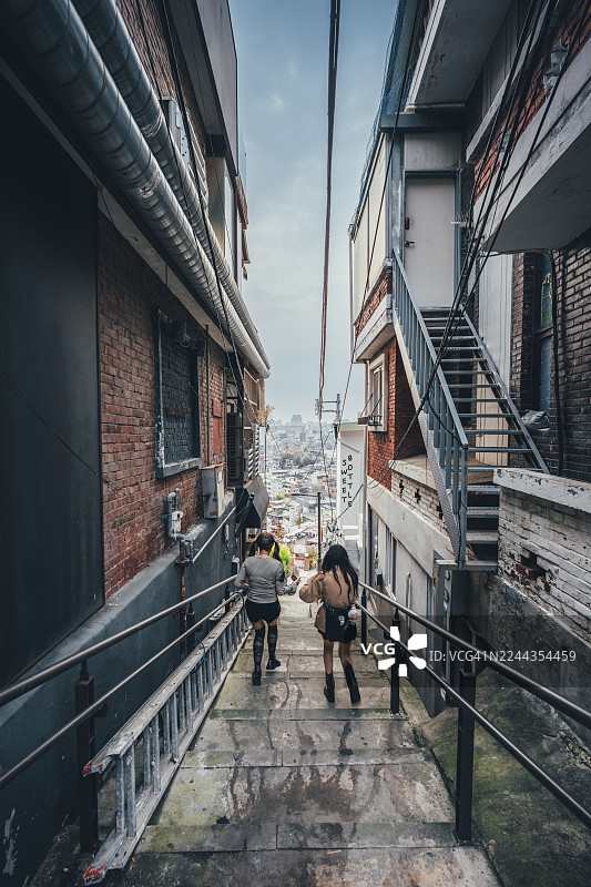 两名女子在韩国首尔梨泰院万圣节期间走在狭窄的小巷里图片素材