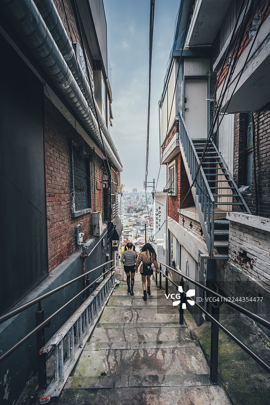 韩国首尔梨泰院万圣节，两位女性走在狭窄的楼梯上图片素材