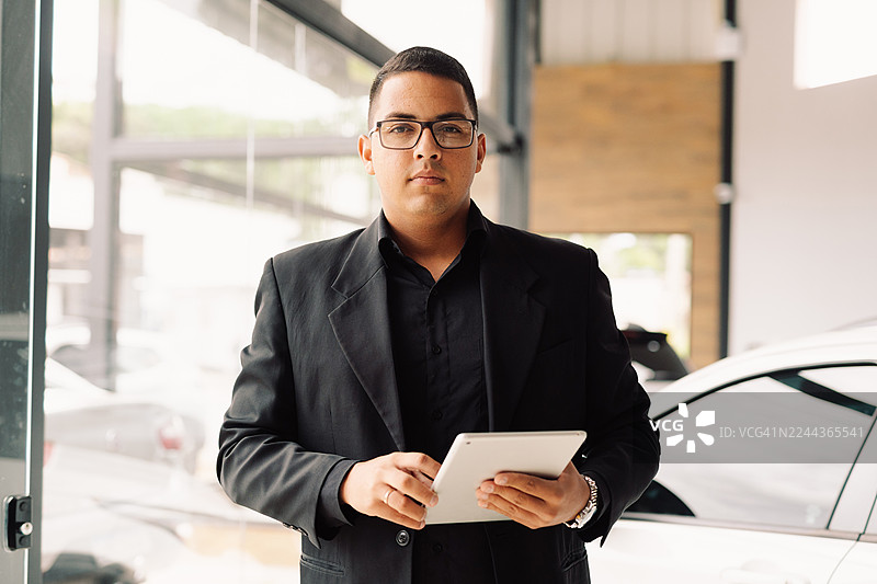 自信的汽车销售员在汽车经销商处图片素材