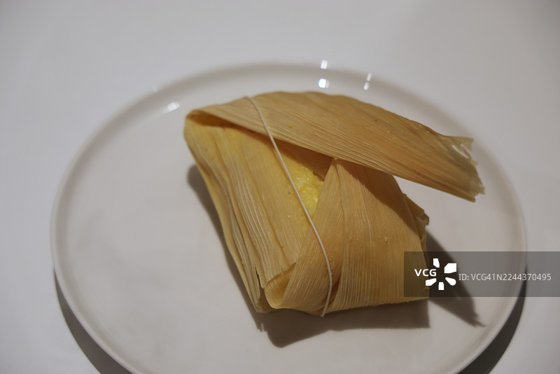 盘子里的奶酪番石榴馅玉米蛋糕（一种传统的哥伦比亚玉米蛋糕，内含奶酪和番石榴酱，用玉米叶包裹并蒸熟）图片素材