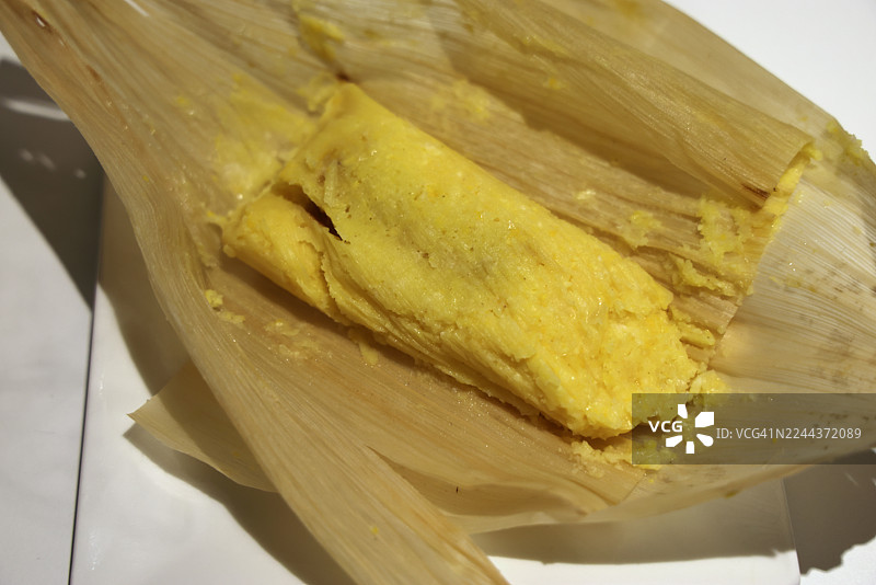 用奶酪和番石榴包裹（传统的哥伦比亚玉米蛋糕，内填奶酪和番石榴酱，用玉米叶包裹并蒸熟）放在盘子里图片素材