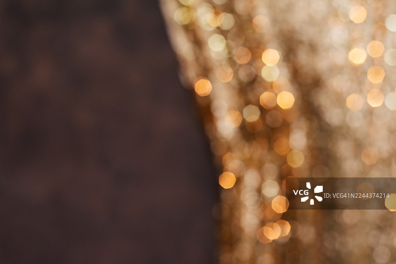 金色闪亮亮片背景。模糊的抽象背景，带有发光灯光。节日背景。图片素材