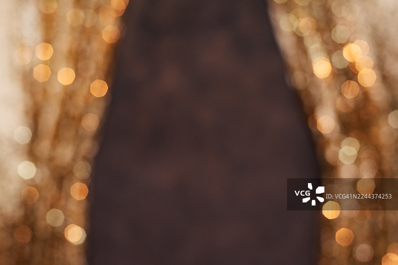 金色闪亮亮片背景。模糊的抽象背景，带有发光灯饰。节日背景。图片素材