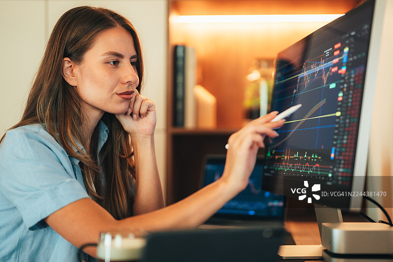 女性加密货币交易员在多个屏幕上分析市场图表图片素材