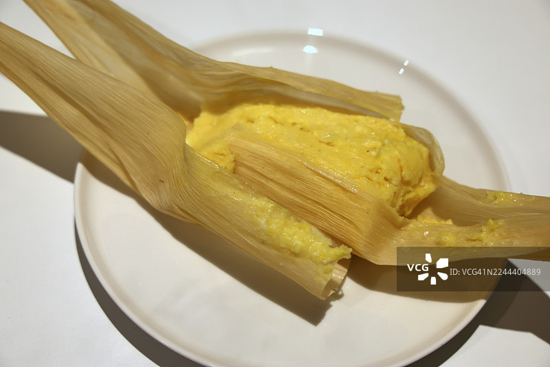 盘子里的奶酪和番石榴馅玉米粽（一种传统哥伦比亚玉米糕，内馅为奶酪和番石榴酱，用玉米叶包裹并蒸煮而成）图片素材