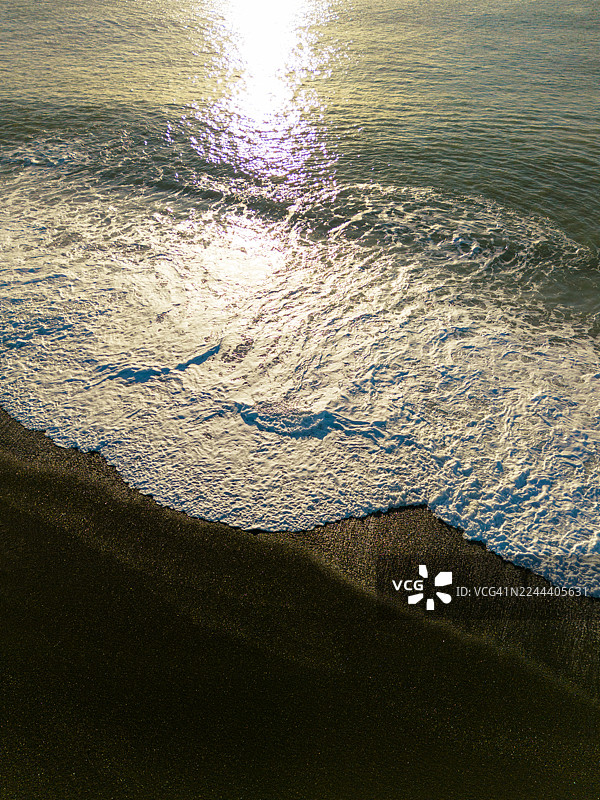 阳光映照在海滩的海浪上图片素材