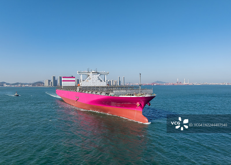 一艘粉色、空载的新集装箱船在青岛城市天际线前航行图片素材