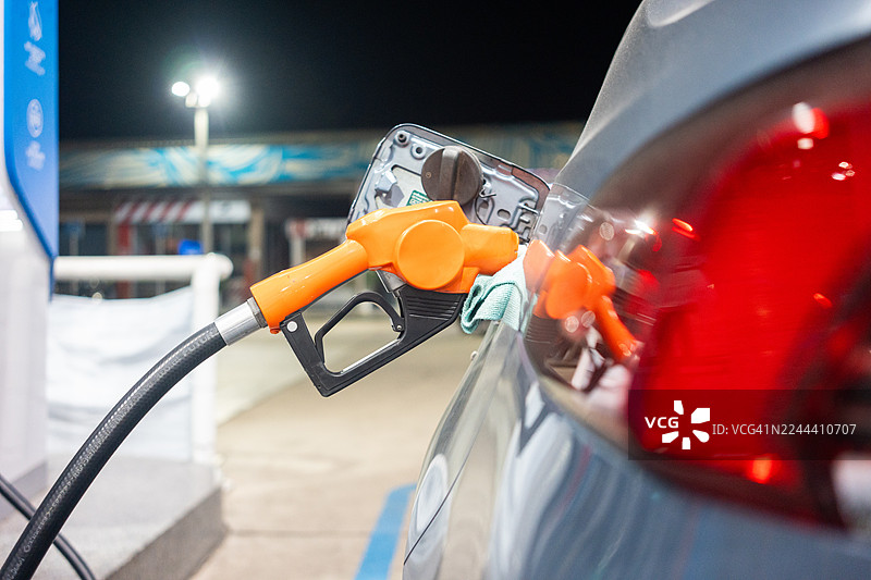 白色汽车在加油站加油，油箱加注口安装了加油阀。图片素材