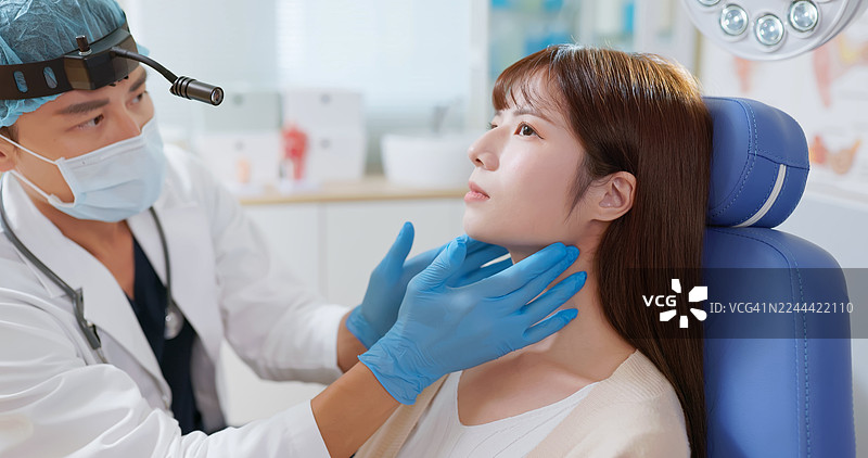 亚洲耳鼻喉科医生触诊年轻女性患者的喉咙图片素材