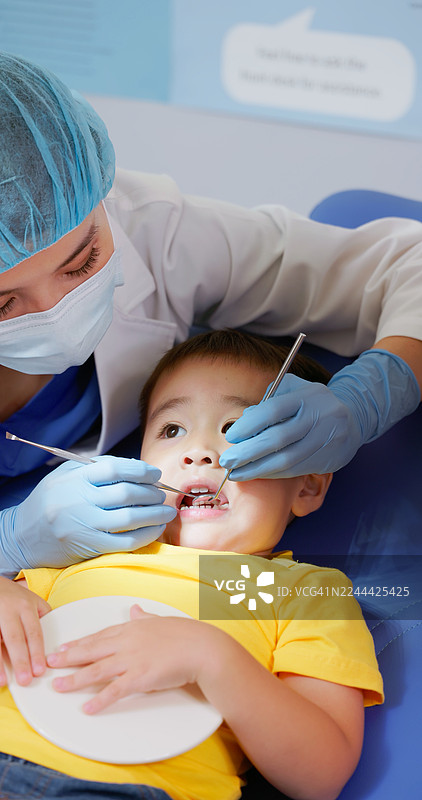 亚裔女牙医正在检查男孩患者的牙齿图片素材