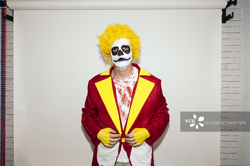 万圣节男子戴着恐怖小丑骷髅妆和黄色假发图片素材