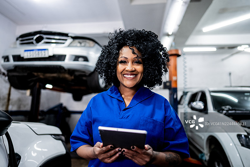 女机械师在维修店使用数码平板电脑拍摄肖像图片素材