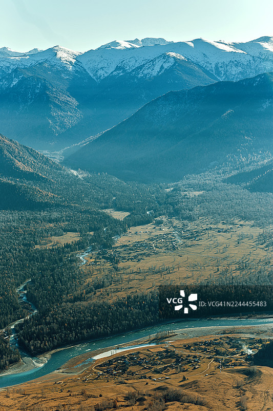 雪山连绵的山谷背景，河流蜿蜒，山丘葱郁，蓝天澄澈。图片素材