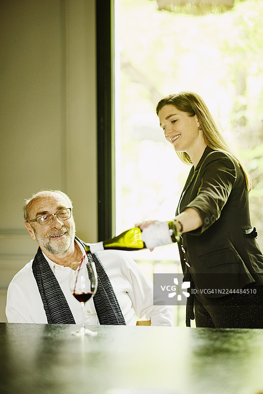 侍酒师从中景为一位年长男宾斟酒图片素材