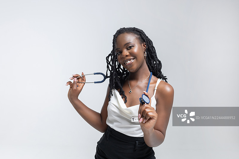 一位微笑的女性医疗专业人士，戴着听诊器，为医疗照片摆姿势。图片素材