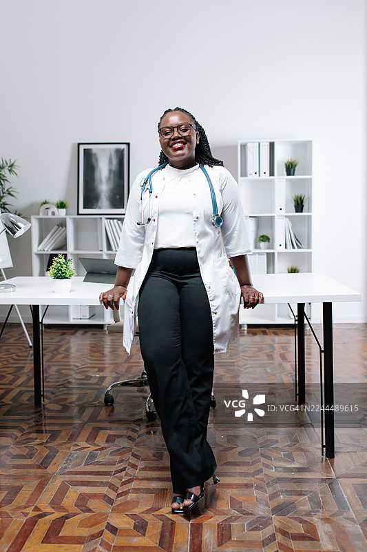 一位自信的女医生在现代诊所里，配戴听诊器并面带微笑图片素材