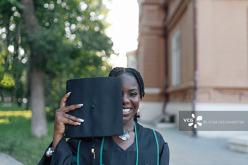 毕业生在户外毕业典礼上，手持毕业帽，脸上洋溢着成功的喜悦。图片素材