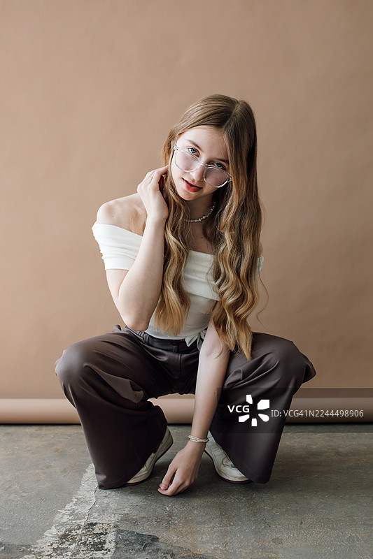 身穿露肩白上衣和阔腿裤的年轻女子时尚肖像照图片素材