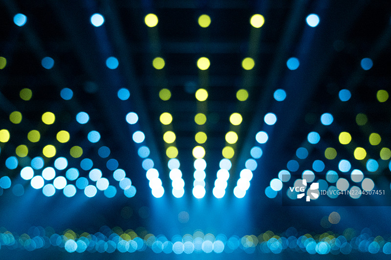一张模糊的抽象图片，展示了排列成行的发光蓝色灯光，在黑暗的背景下营造出未来隧道般的效果。图片素材