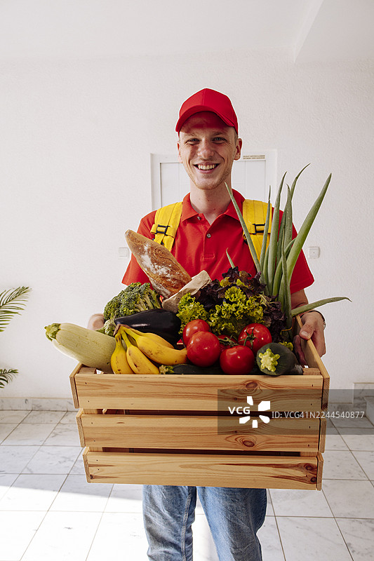 面带微笑的送货员为顾客准备木箱装的新鲜杂货取货图片素材