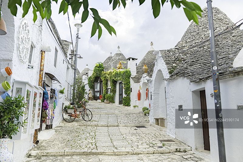 意大利阿尔贝罗贝洛——在历史悠久的联合国教科文组织世界遗产普利亚村庄里,鹅卵石街道旁矗立着传统的特鲁利房屋,房屋拥有标志性的锥形石头屋顶,展示了意大利的文化、建筑以及欧洲热门旅游目的地。图片素材